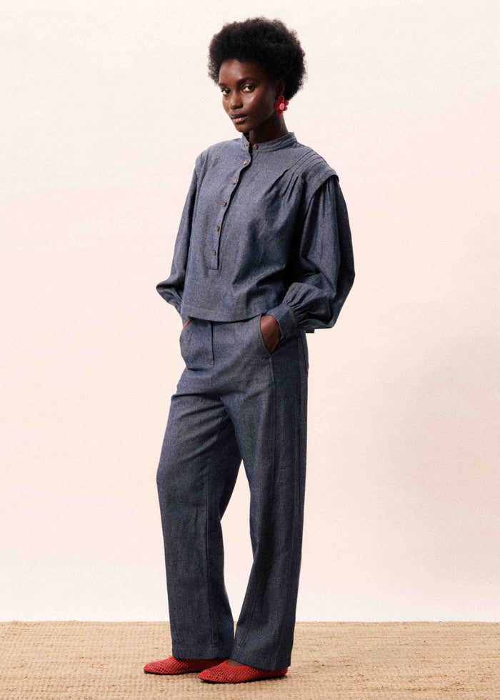Woman wearing navy blue denim two-piece set with button-up top and straight-leg pants.