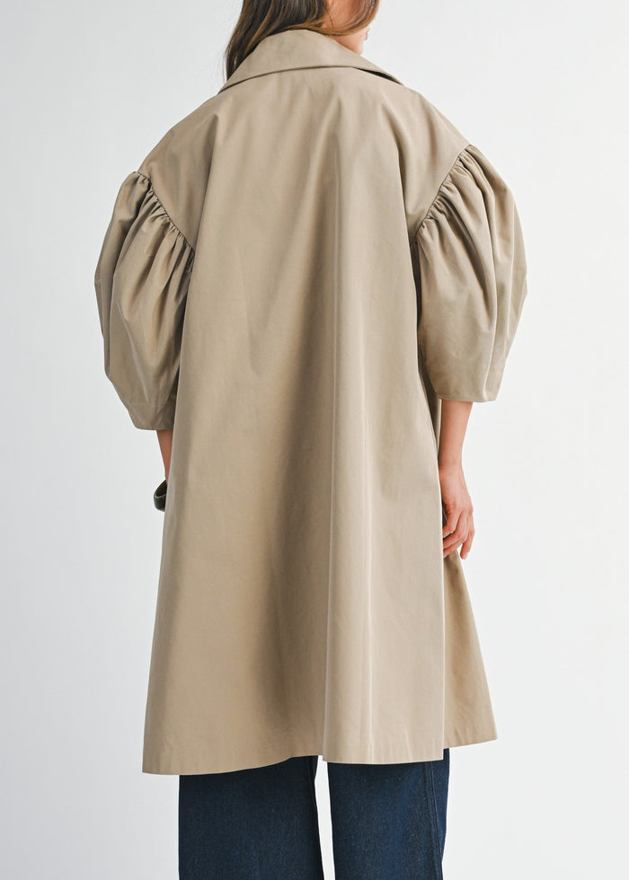 Person wearing a beige trench coat on a white background