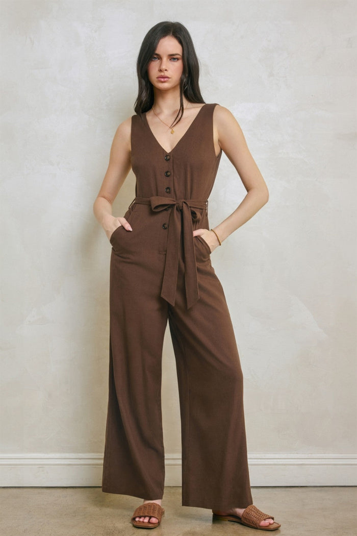 Brown sleeveless jumpsuit with V-neckline, button front, tie waist, and front pockets.