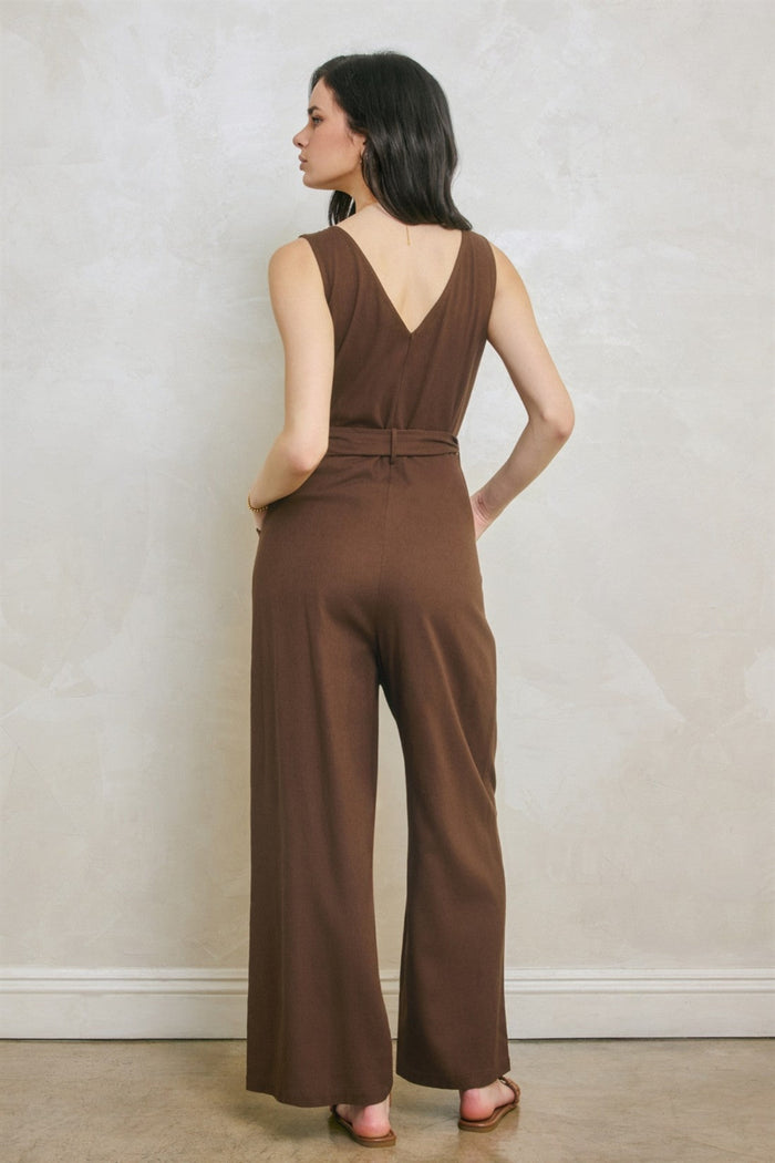 Woman wearing brown sleeveless jumpsuit with V-neckline and wide-leg pants, shown from back view.