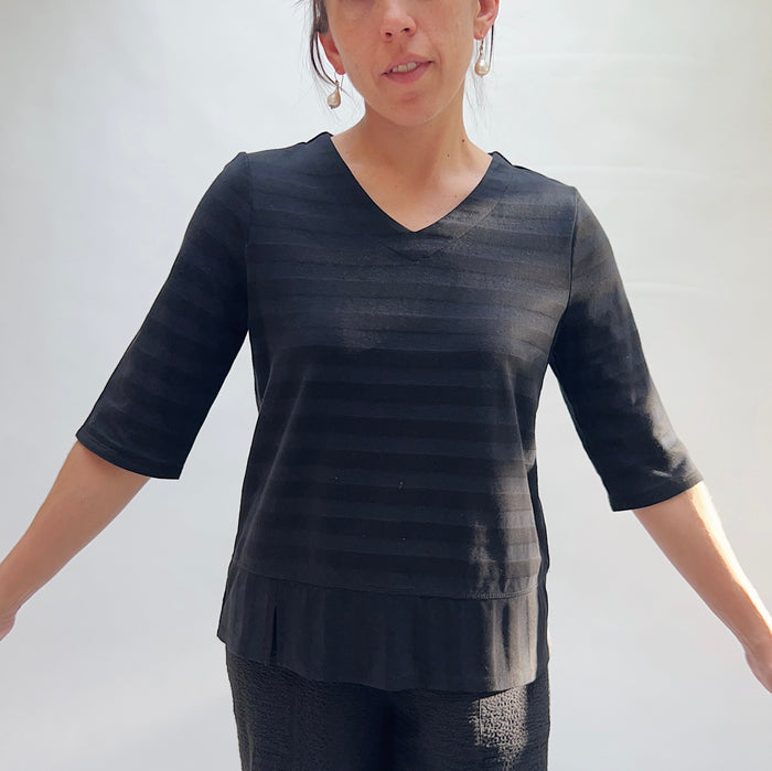 Full front view of model wearing Habitat black shadow stripe elbow sleeve top, showing V-neckline, relaxed fit, elbow-length sleeves, and layered hem with side slits