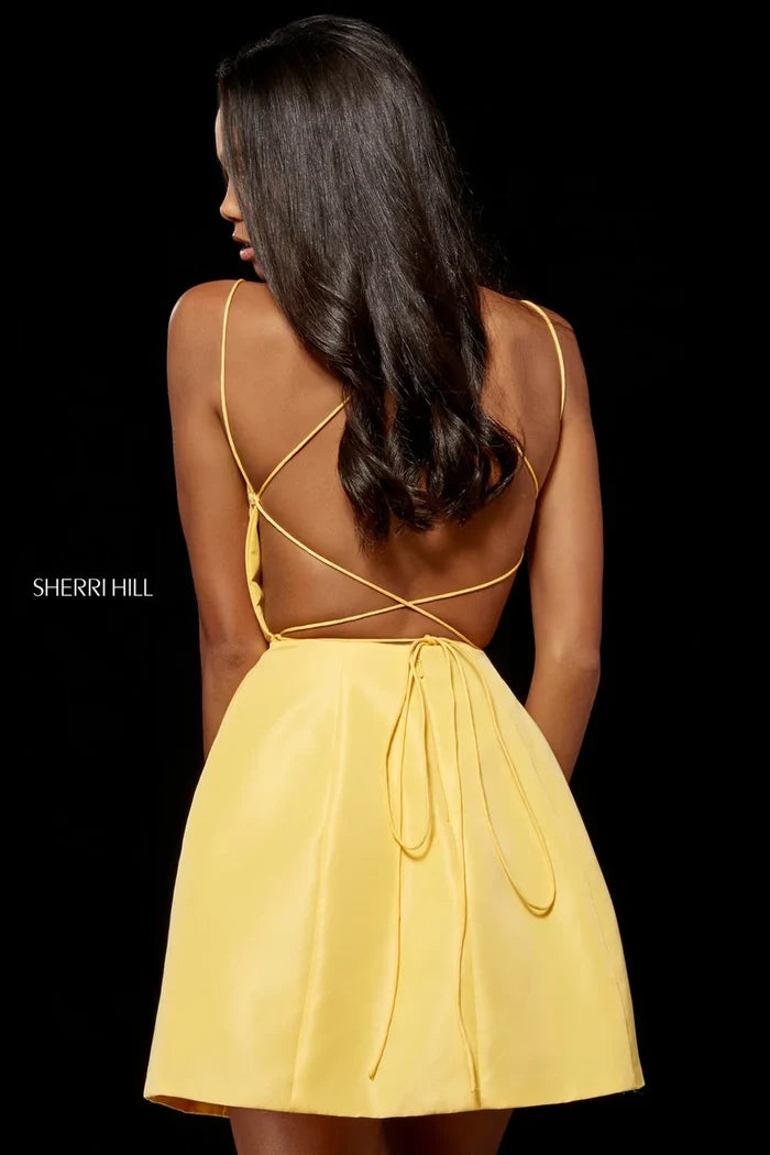 A woman shown from the back wearing a bright yellow spaghetti-strap dress with an open back and tie detail, photographed against a solid black background. The Sherri Hill brand name is visible on the left side.