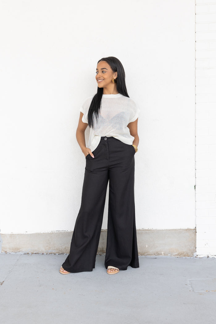 Black wide-leg pants with front pockets and button waist, styled with white t-shirt.