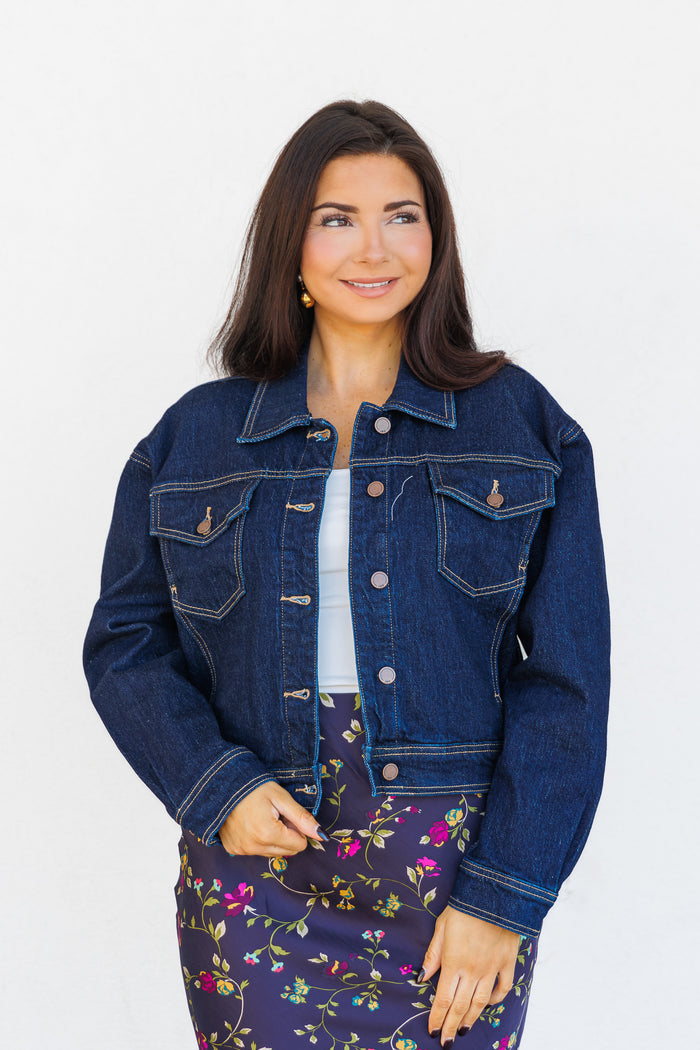 Dark blue denim jacket with button front, collar, and chest pockets with contrast stitching.