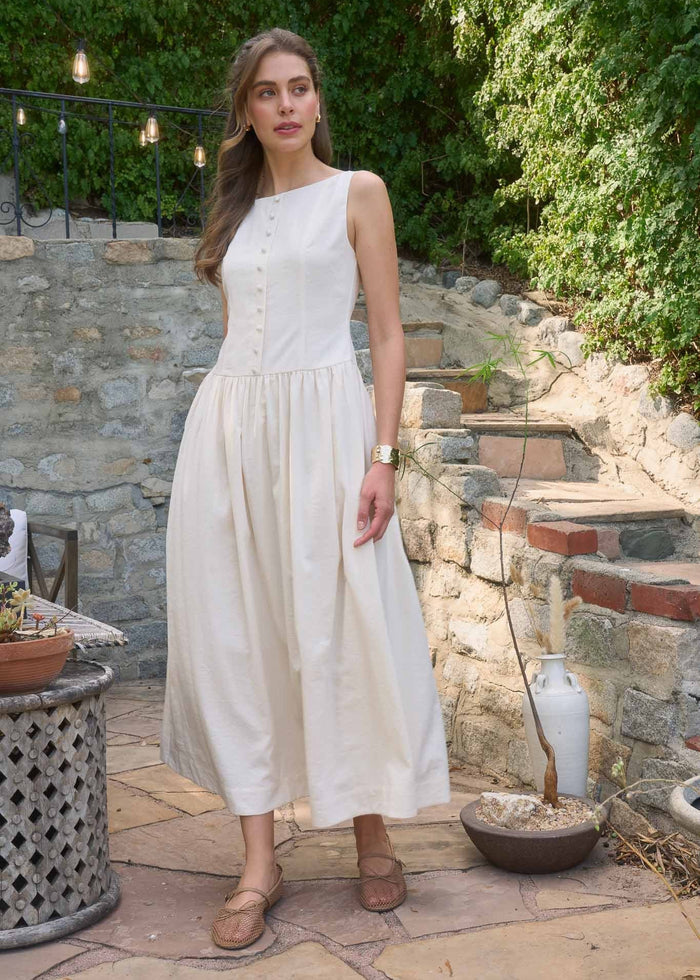 White sleeveless midi dress with button front bodice and pleated skirt.