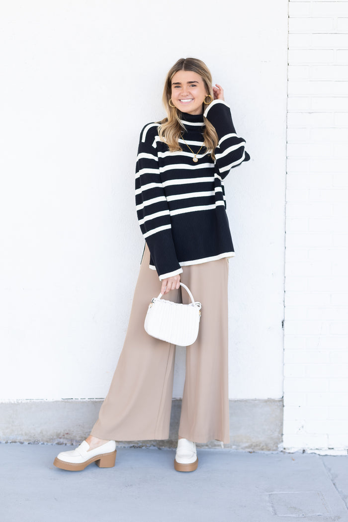 White loafers with chunky tan platform sole worn on feet with beige pants.
