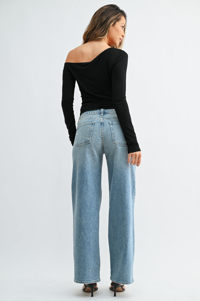 Woman wearing light wash wide-leg jeans with a black off-shoulder long-sleeve top, shown from back view.