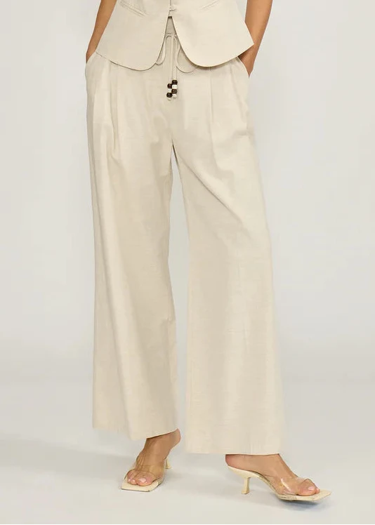 Cream-colored wide-leg pants with drawstring waist and side pockets, shown with matching vest.