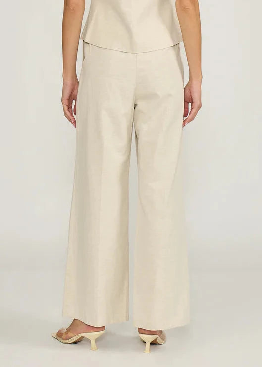Cream wide-leg pants with high waist and straight silhouette on model wearing beige heels.