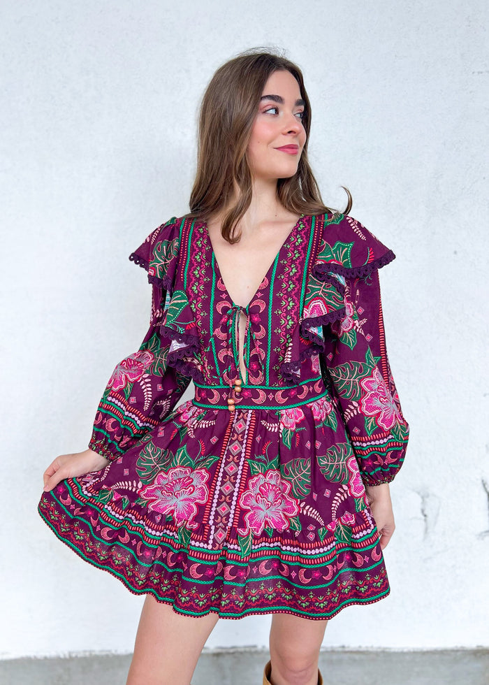 Purple mini dress with multicolored floral and geometric embroidery, puffed sleeves, V-neckline, and tie-front closure.