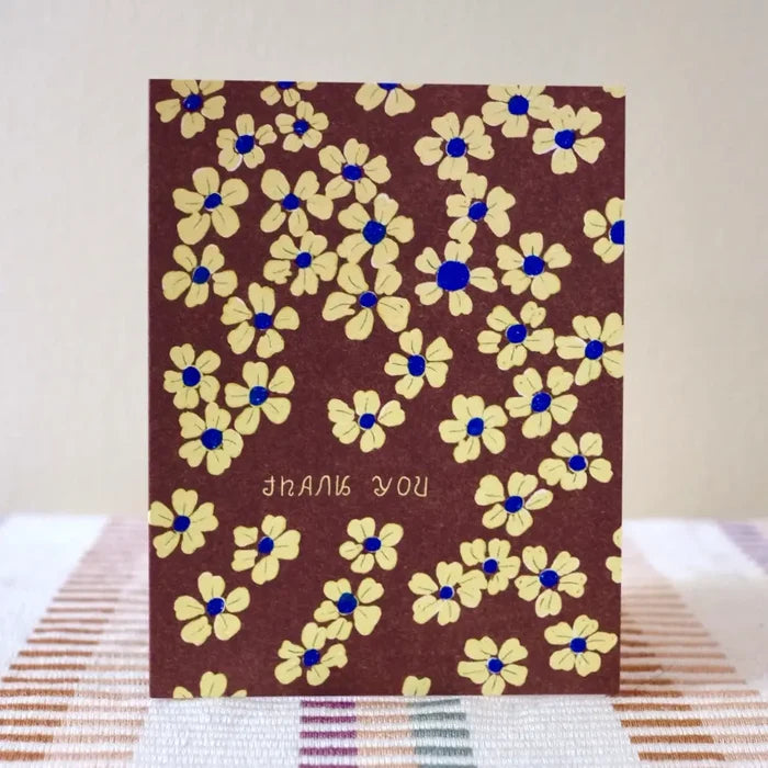 Card with floral pattern and 'thank you' text on a striped surface