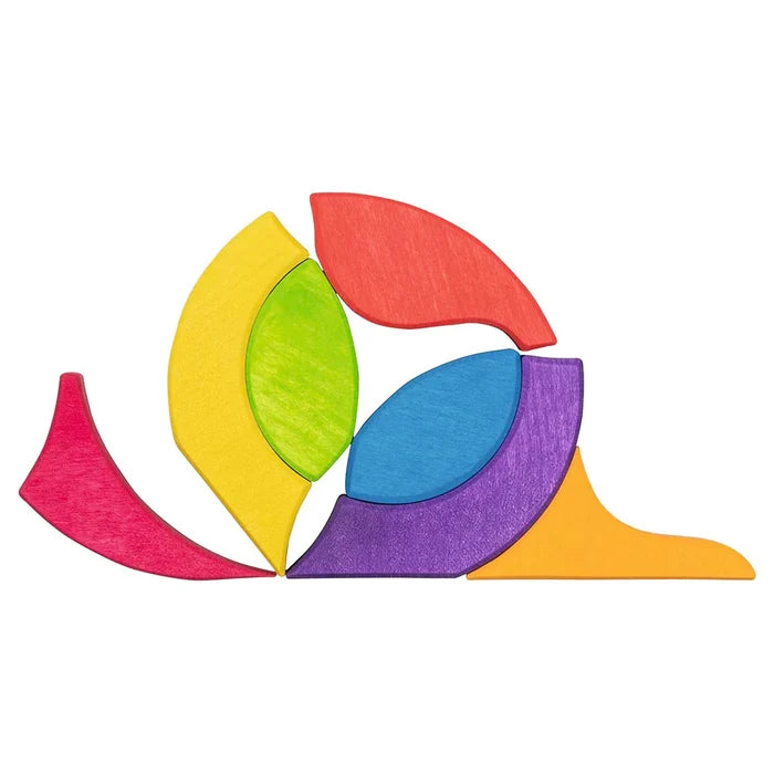 Goki Butterfly Mariposa Tile Puzzle pieces arranged in free play outside the frame, forming a circular pinwheel shape using curved and leaf-shaped maple wood pieces in red, orange, yellow, green, blue, and purple on a white background