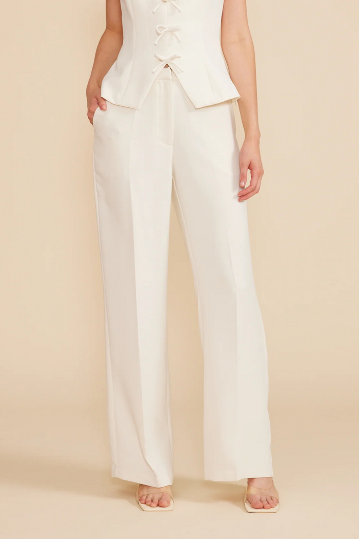 Cream wide-leg pants with high waist and straight silhouette paired with matching lace-up vest top.