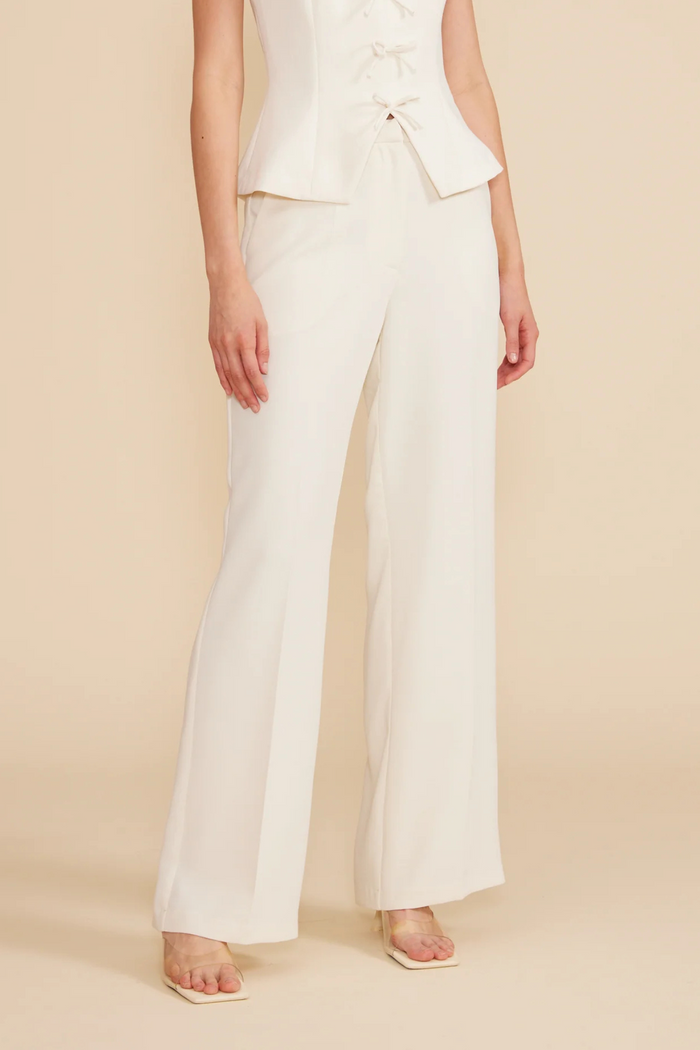 Cream wide-leg pants with high waist and straight silhouette, paired with matching sleeveless top.