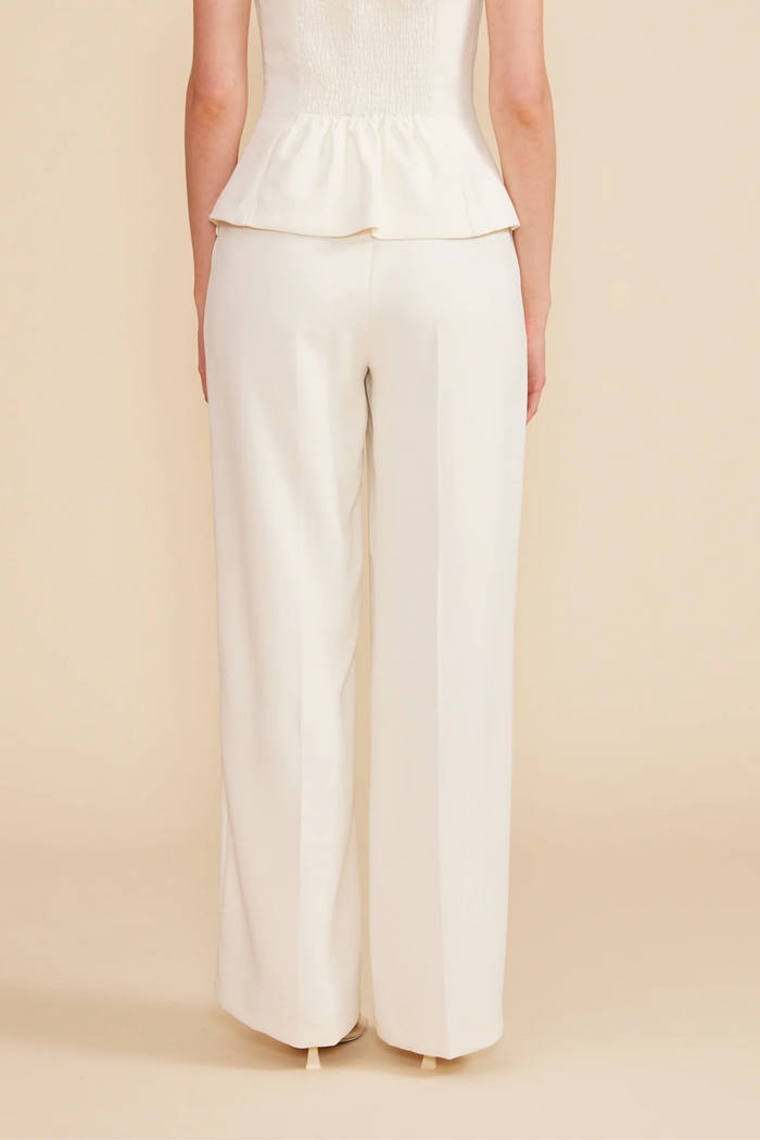 Cream wide-leg pants with high waist and straight silhouette, shown from back view on model.