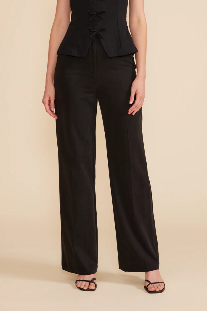 Black wide-leg pants with full-length straight silhouette worn with matching sleeveless top.