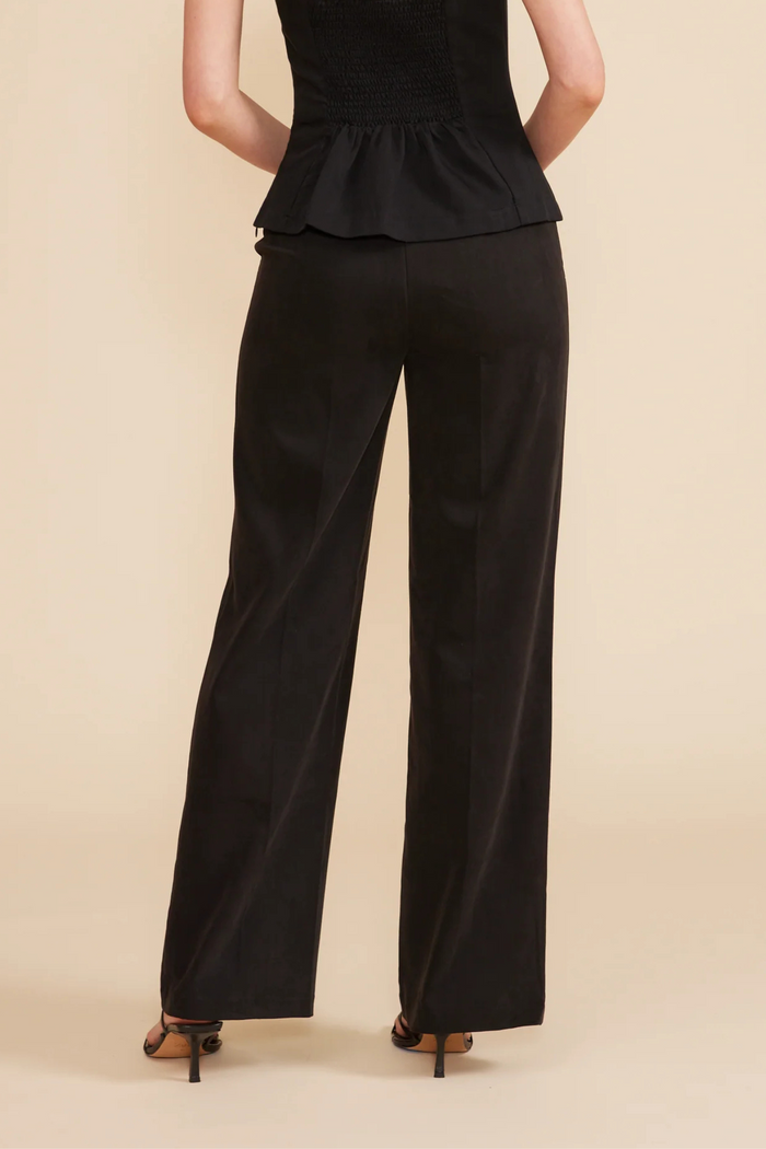 Black wide-leg pants with elastic waistband worn with black peplum top and heeled sandals.