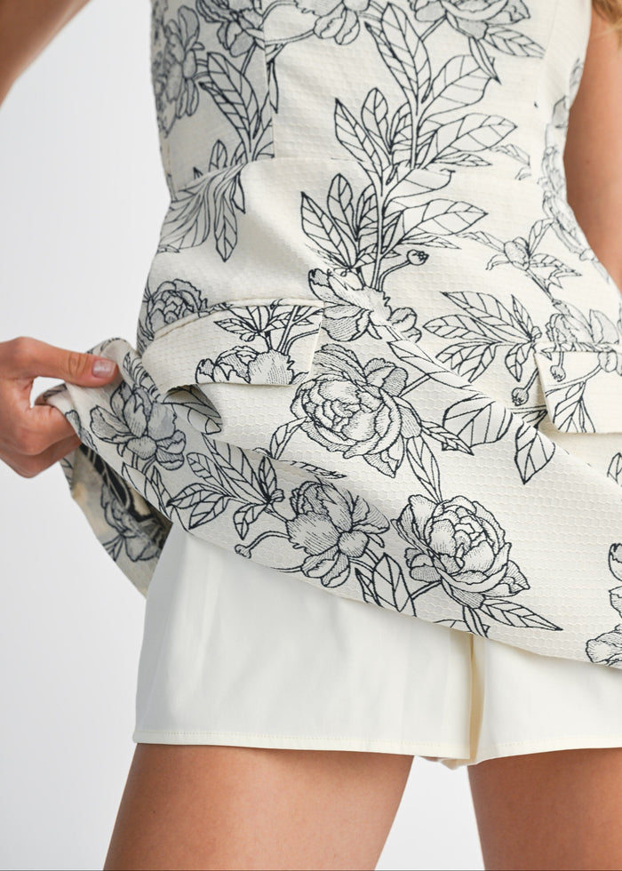 Cream mini dress with black line-drawn floral and leaf jacquard pattern throughout bodice and skirt.