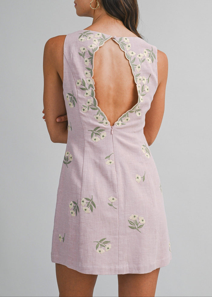Lavender sleeveless mini dress with white floral embroidery and open back detail.