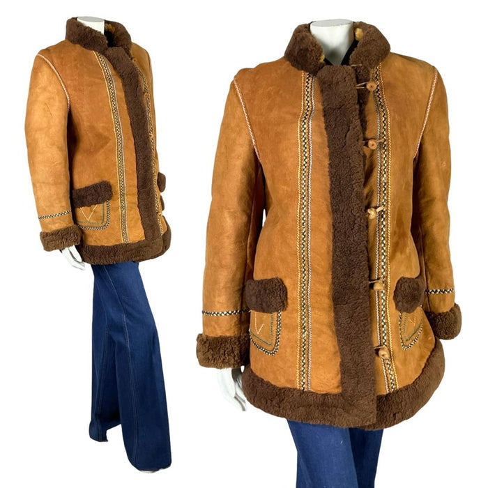 Shrinking Violets Vintage 60s 70s brown suede shearling boho hippy coat with rainbow embroidery trim on a white mannequin wearing blue flared jeans