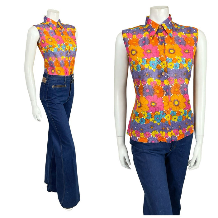 shrinking violets vintage 60s 70s sleeveless purple orange and pink floral dagger collar shirt on a white mannequin wearing blue flared jeans