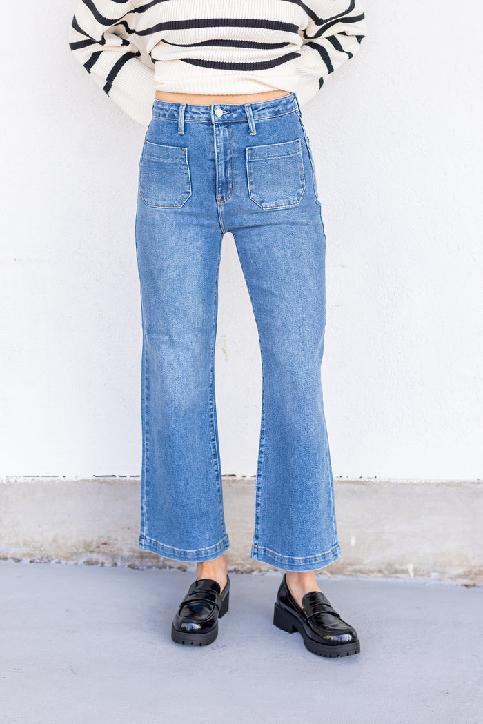 Medium blue denim jeans with high waist, front patch pockets, and cropped flare leg.