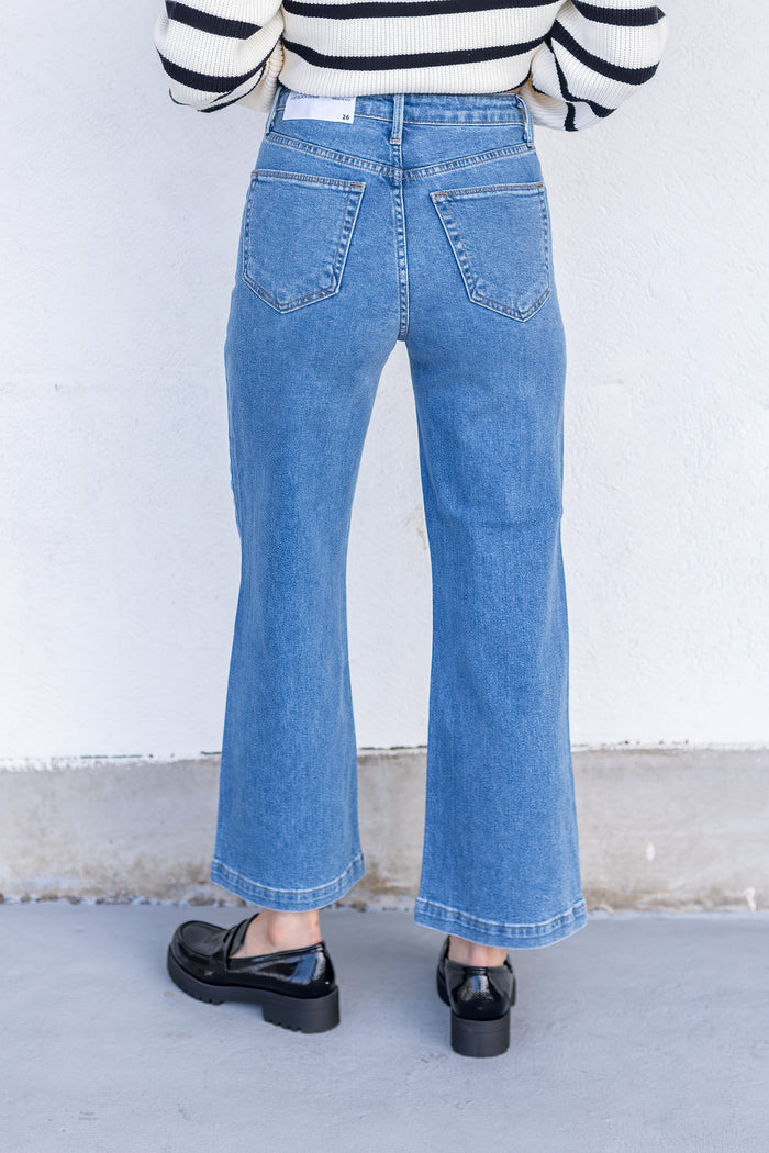 Back view of blue denim flared jeans with five-pocket styling and contrast stitching.