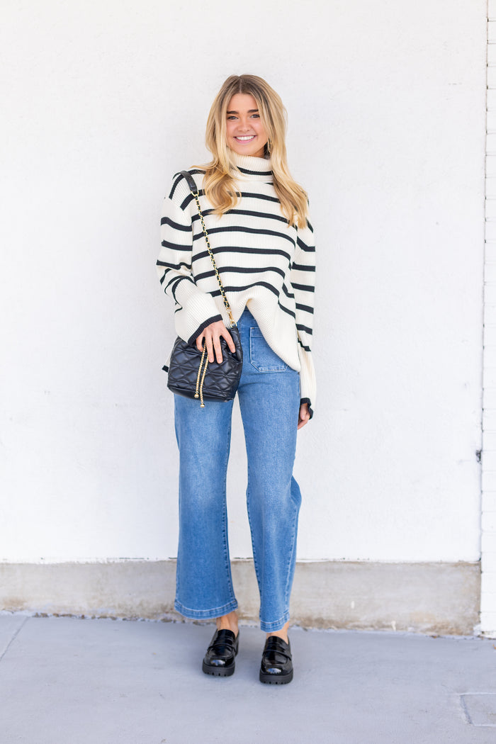 Blue straight-leg denim jeans with classic five-pocket styling shown on model with striped sweater.